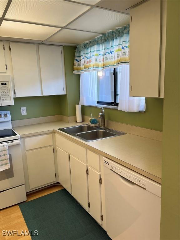 kitchen featuring white appliances, light countertops, a sink, and wood finished floors