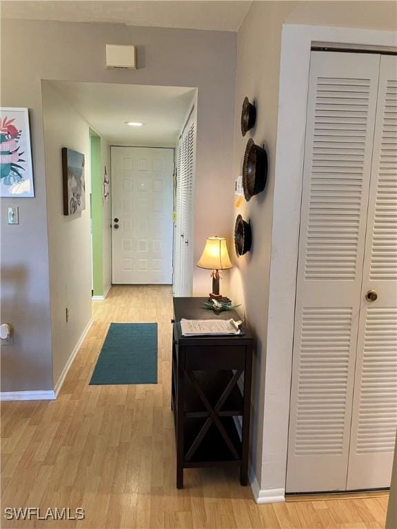 hallway featuring light wood-style flooring and baseboards