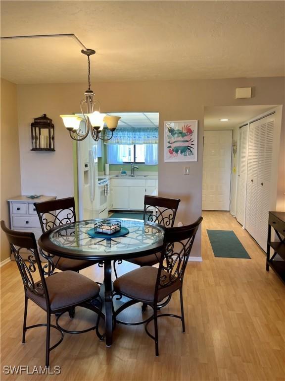 dining space with light wood-style flooring, baseboards, and a notable chandelier