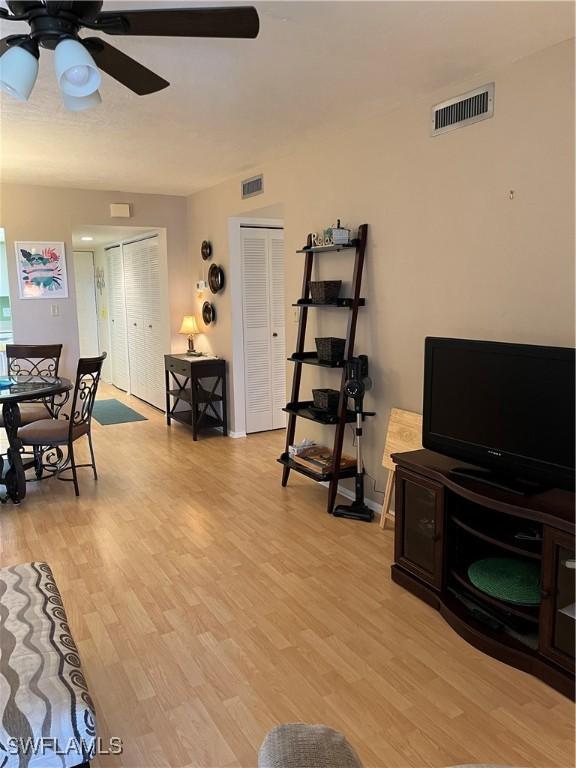 living room with baseboards, light wood-type flooring, visible vents, and a ceiling fan