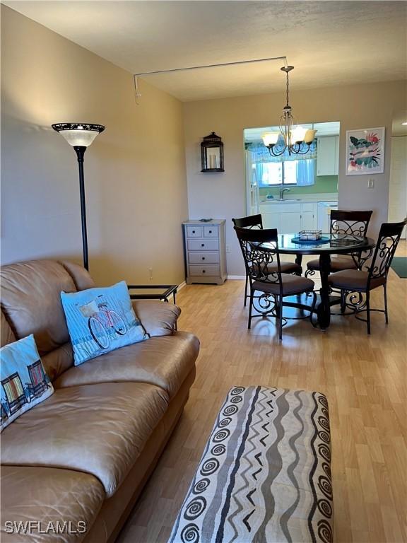 living room with light wood-type flooring, an inviting chandelier, and baseboards