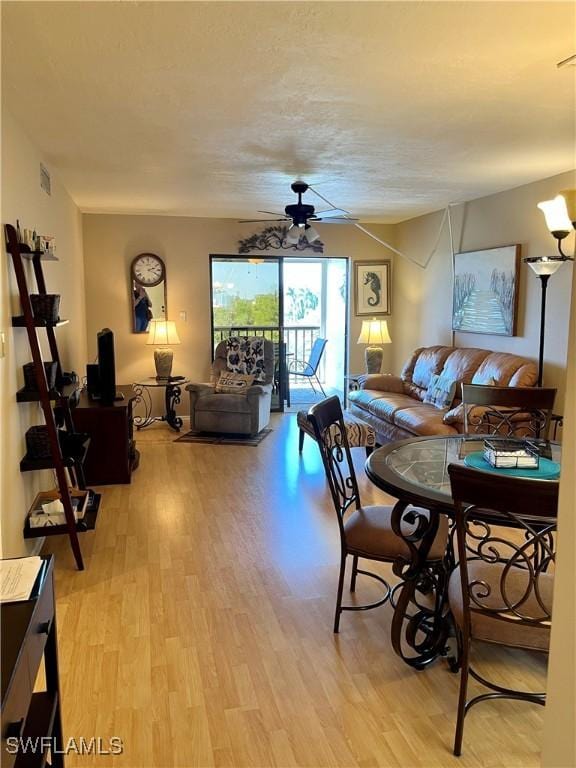 living room with visible vents, light wood finished floors, and a ceiling fan