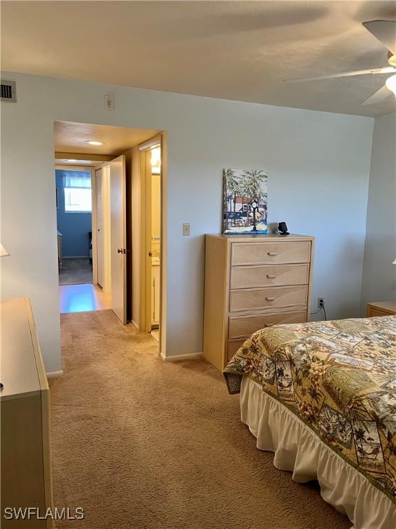 bedroom featuring baseboards, visible vents, a ceiling fan, and light colored carpet