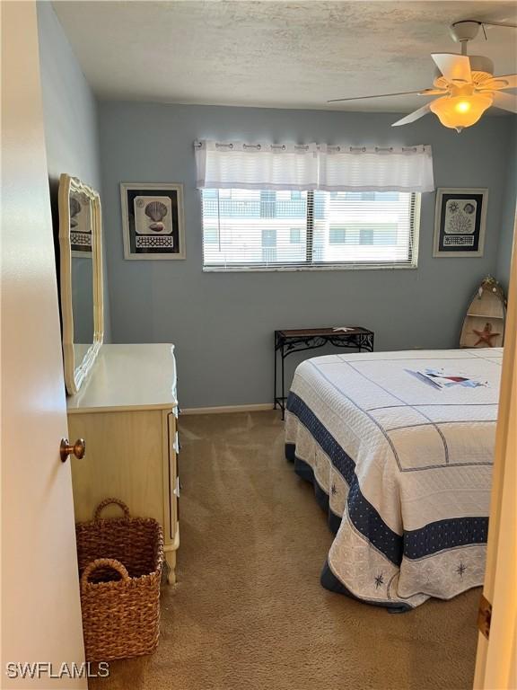 bedroom with carpet floors, a textured ceiling, baseboards, and a ceiling fan