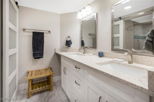 bathroom featuring double vanity, a stall shower, baseboards, and a sink