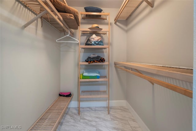 walk in closet featuring marble finish floor