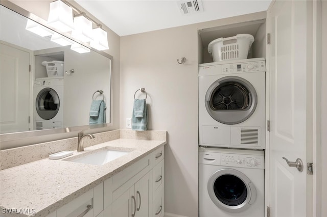 laundry area with visible vents, stacked washer and clothes dryer, and a sink