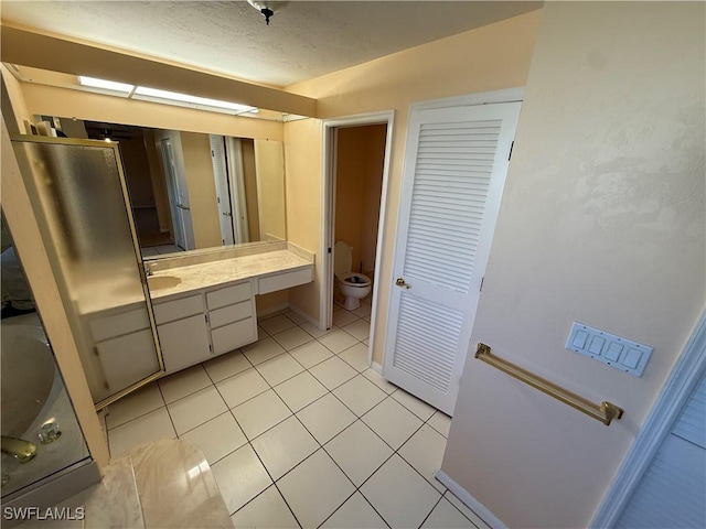 full bathroom featuring a textured ceiling, vanity, toilet, and tile patterned floors