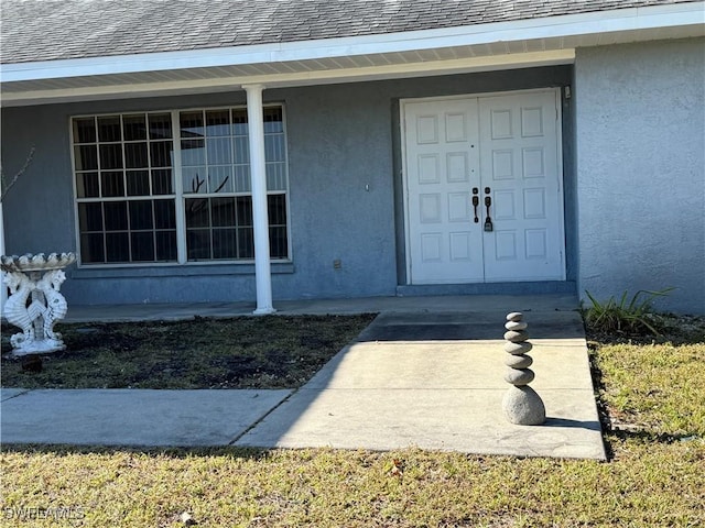 property entrance with a shingled roof and stucco siding