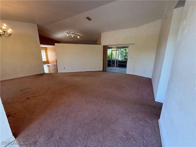 empty room with carpet floors, lofted ceiling, visible vents, track lighting, and a chandelier