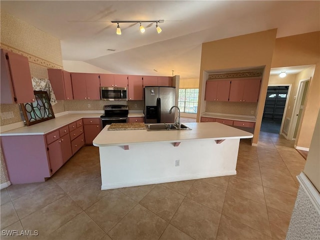 kitchen featuring lofted ceiling, stainless steel appliances, a sink, light countertops, and a center island with sink