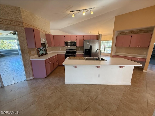 kitchen featuring stainless steel appliances, light countertops, vaulted ceiling, a sink, and wallpapered walls