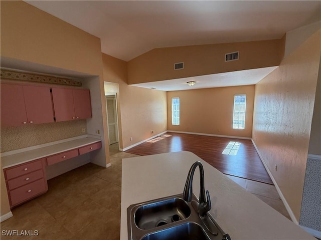 kitchen featuring vaulted ceiling, visible vents, a sink, and open floor plan