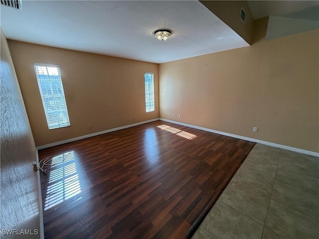 empty room with baseboards, visible vents, and wood finished floors