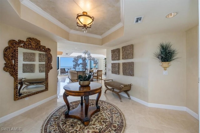 hallway featuring a raised ceiling, crown molding, visible vents, and baseboards