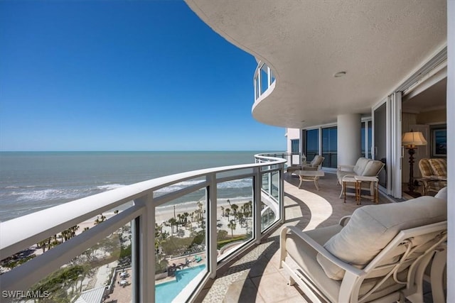 balcony with a water view and a view of the beach