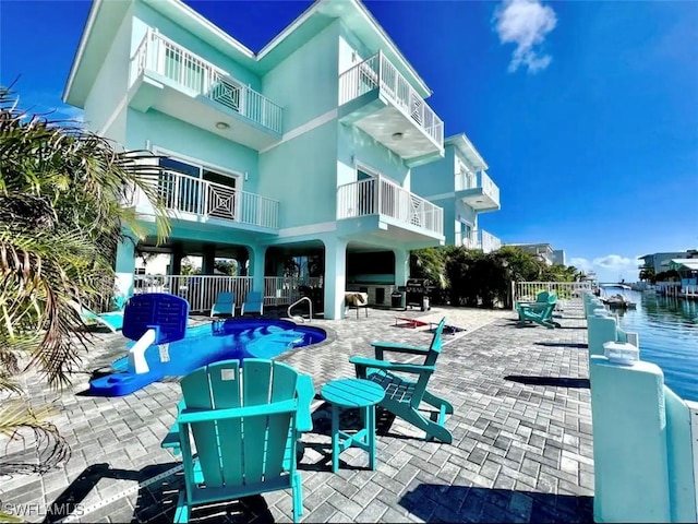 back of property with stucco siding, a pool, and a patio area