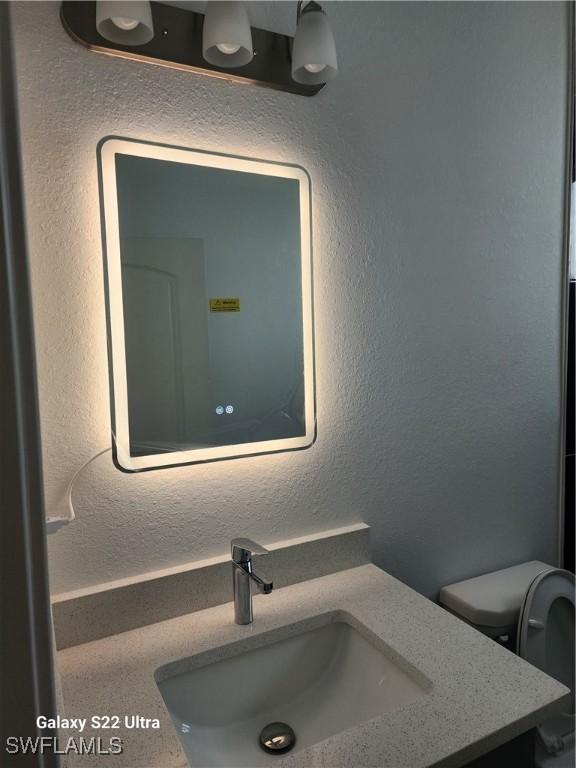 651 Knapp St, Lehigh Acres, FL 33974 - interior details featuring toilet, a textured wall, and vanity