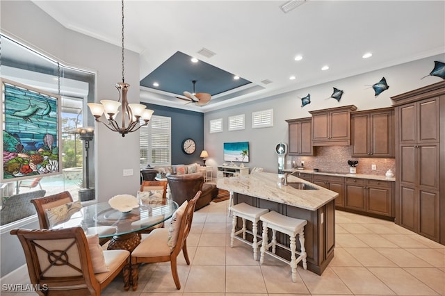 kitchen featuring a sink, a tray ceiling, tasteful backsplash, and light tile patterned floors