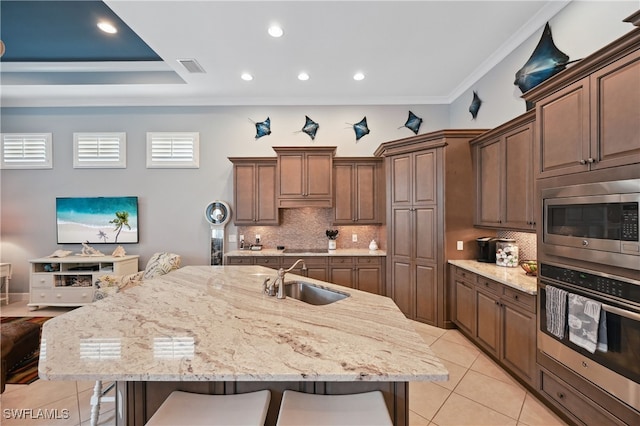 kitchen with a kitchen bar, visible vents, ornamental molding, a sink, and stainless steel appliances