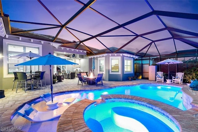 view of pool featuring a lanai, a pool with connected hot tub, and a patio