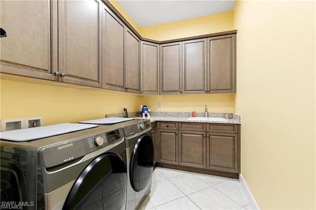 clothes washing area featuring baseboards, light tile patterned floors, cabinet space, independent washer and dryer, and a sink