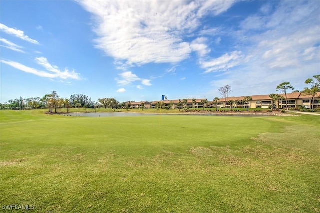 surrounding community with a water view and a lawn