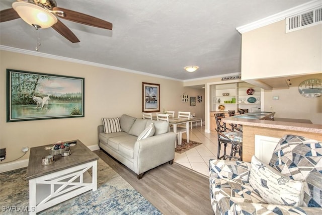 living room featuring visible vents, ornamental molding, a ceiling fan, light tile patterned flooring, and baseboards