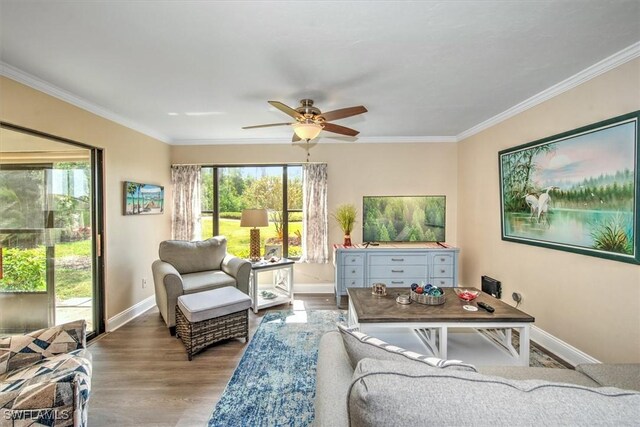 living room with baseboards, ceiling fan, wood finished floors, and crown molding