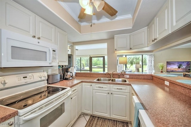 kitchen with white appliances, a tray ceiling, crown molding, white cabinetry, and a sink