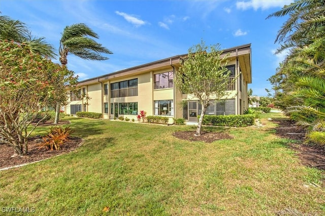 rear view of house with a lawn and stucco siding