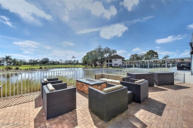 view of patio with a hot tub, a water view, and an outdoor fire pit