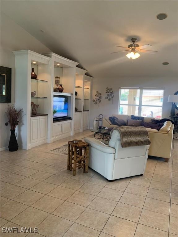 living area with a ceiling fan, lofted ceiling, and light tile patterned floors