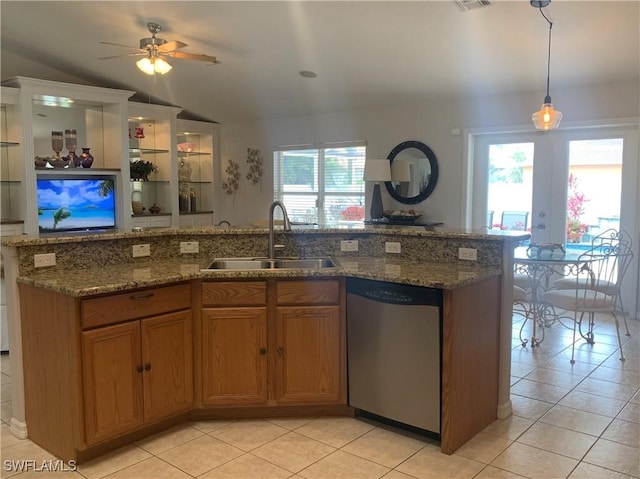 kitchen with a sink, open floor plan, vaulted ceiling, stainless steel dishwasher, and brown cabinets