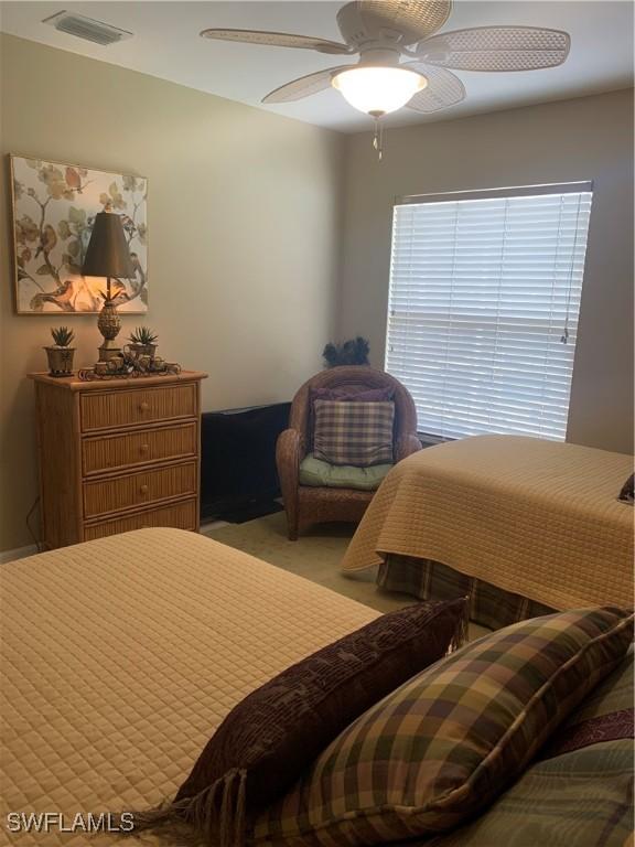 bedroom with visible vents, a ceiling fan, and light colored carpet