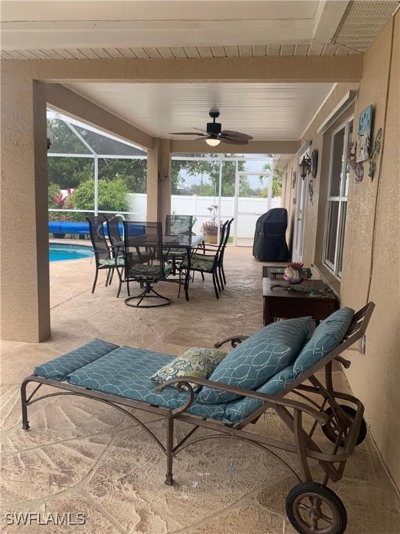 view of patio / terrace featuring a fenced in pool, outdoor dining space, glass enclosure, fence, and ceiling fan