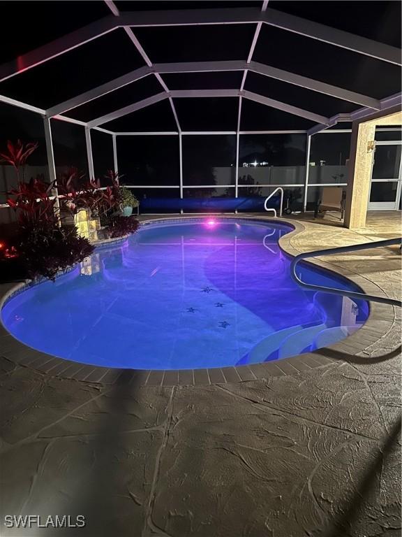 outdoor pool with a patio area and glass enclosure