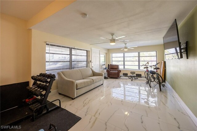 living area featuring marble finish floor, a ceiling fan, and baseboards