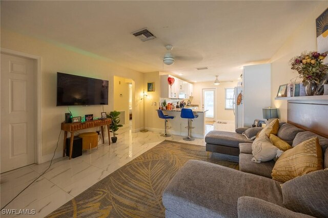 living area featuring visible vents, marble finish floor, a ceiling fan, and baseboards