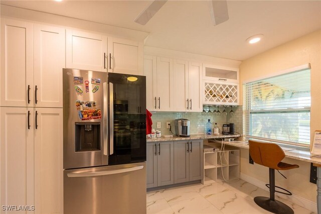 kitchen with white cabinets, light stone counters, stainless steel fridge with ice dispenser, and marble finish floor