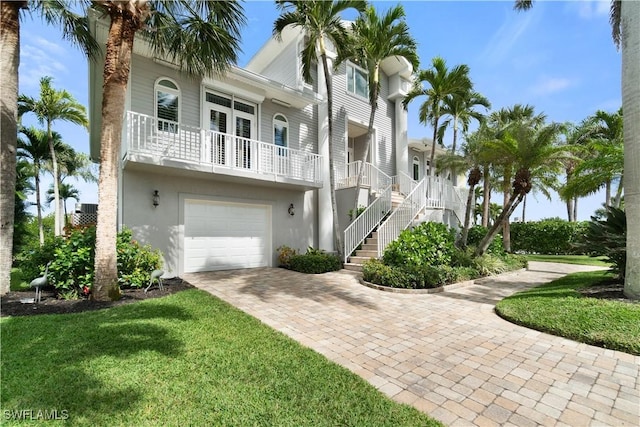 view of property exterior featuring stucco siding, a lawn, driveway, stairway, and a garage