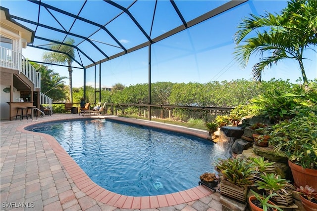 pool featuring stairs, a patio, a lanai, and outdoor dry bar