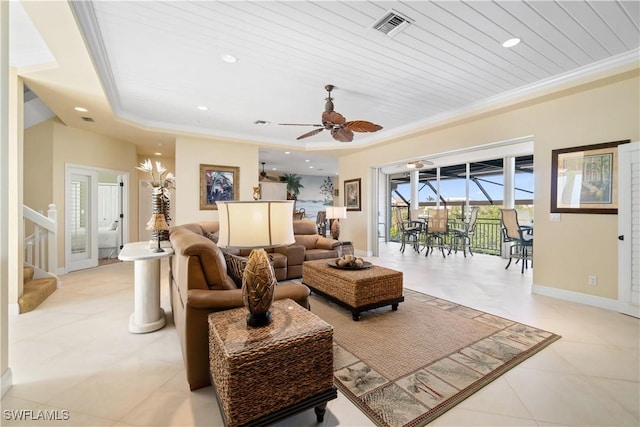 living area featuring visible vents, a raised ceiling, baseboards, and ornamental molding