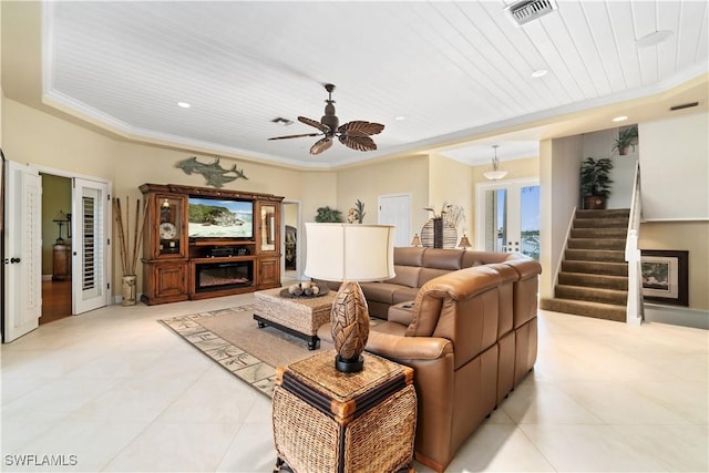 living room featuring visible vents, crown molding, stairs, french doors, and a glass covered fireplace