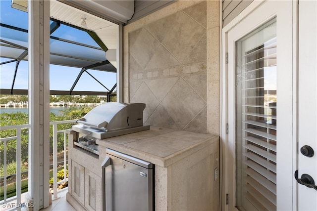 view of patio featuring grilling area, a water view, an outdoor kitchen, and a lanai