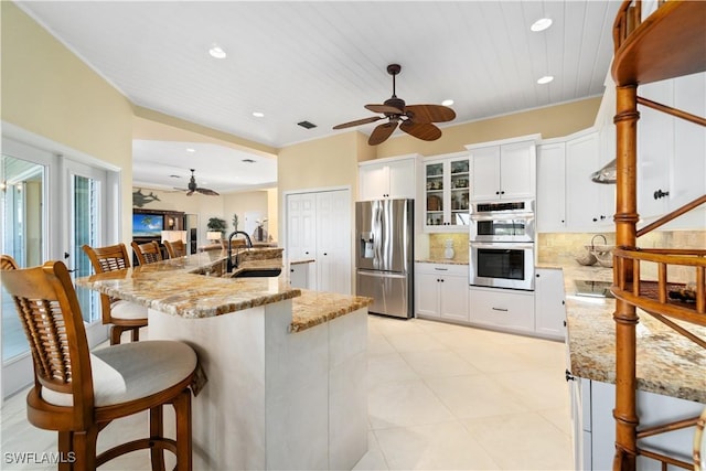 kitchen featuring tasteful backsplash, a kitchen bar, stainless steel appliances, white cabinetry, and a sink