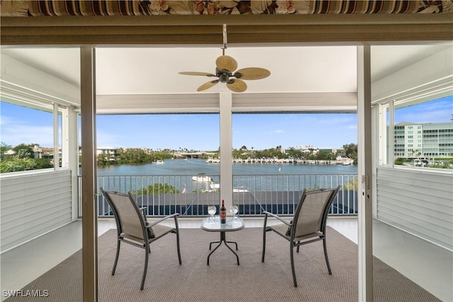 sunroom / solarium with a ceiling fan and a water view