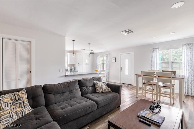 living area with wood finished floors, visible vents, and baseboards