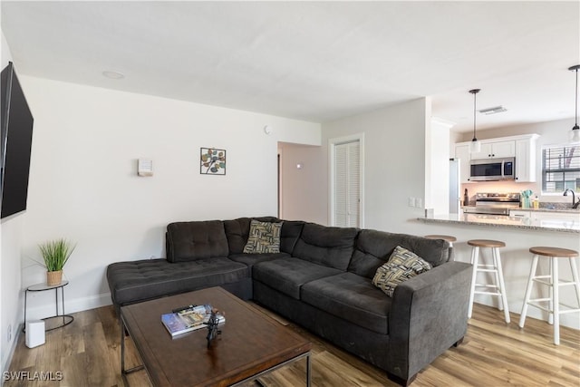 living area with light wood finished floors, visible vents, and baseboards