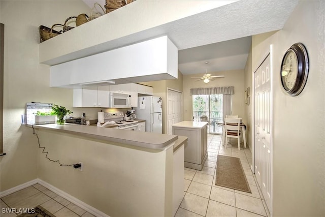 kitchen featuring white appliances, light countertops, a kitchen island, and light tile patterned floors